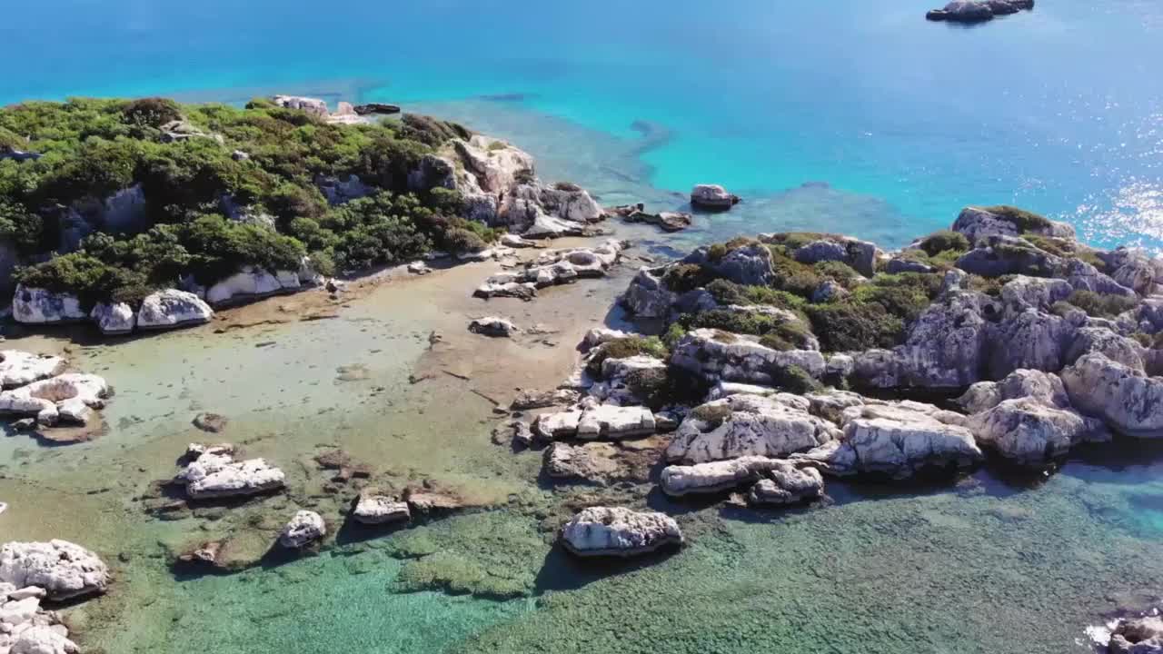 阳光明媚的日子里，蓝色的大海、浅浅的海水和美丽的岩石的鸟瞰图视频素材