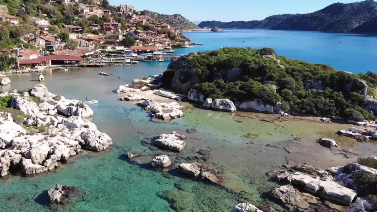 无人机拍摄的美丽的岩石海岸，浅水和村庄(土耳其，凯科瓦)视频素材