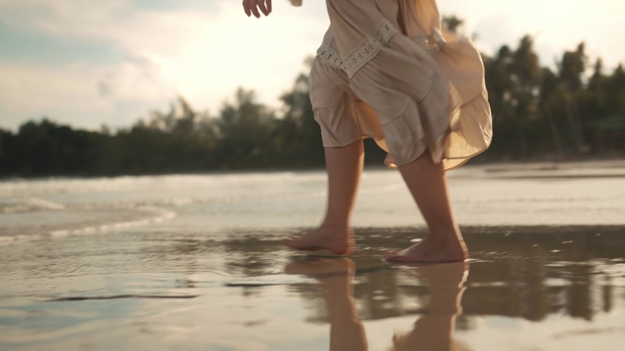 B滚-沙滩上女人的脚沿着海浪走，夏季旅游度假的女游客，慢动作视频素材