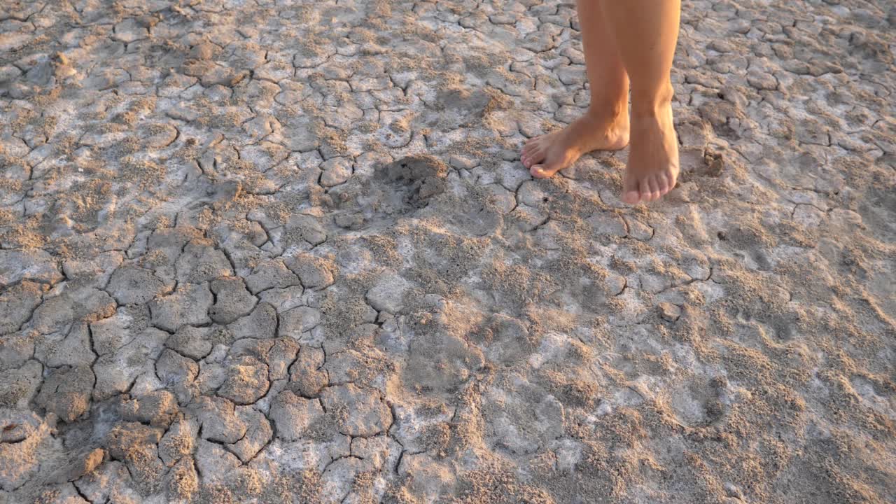 赤脚妇女的腿走在非常干燥开裂的土地上，炎热的夏季气候视频素材