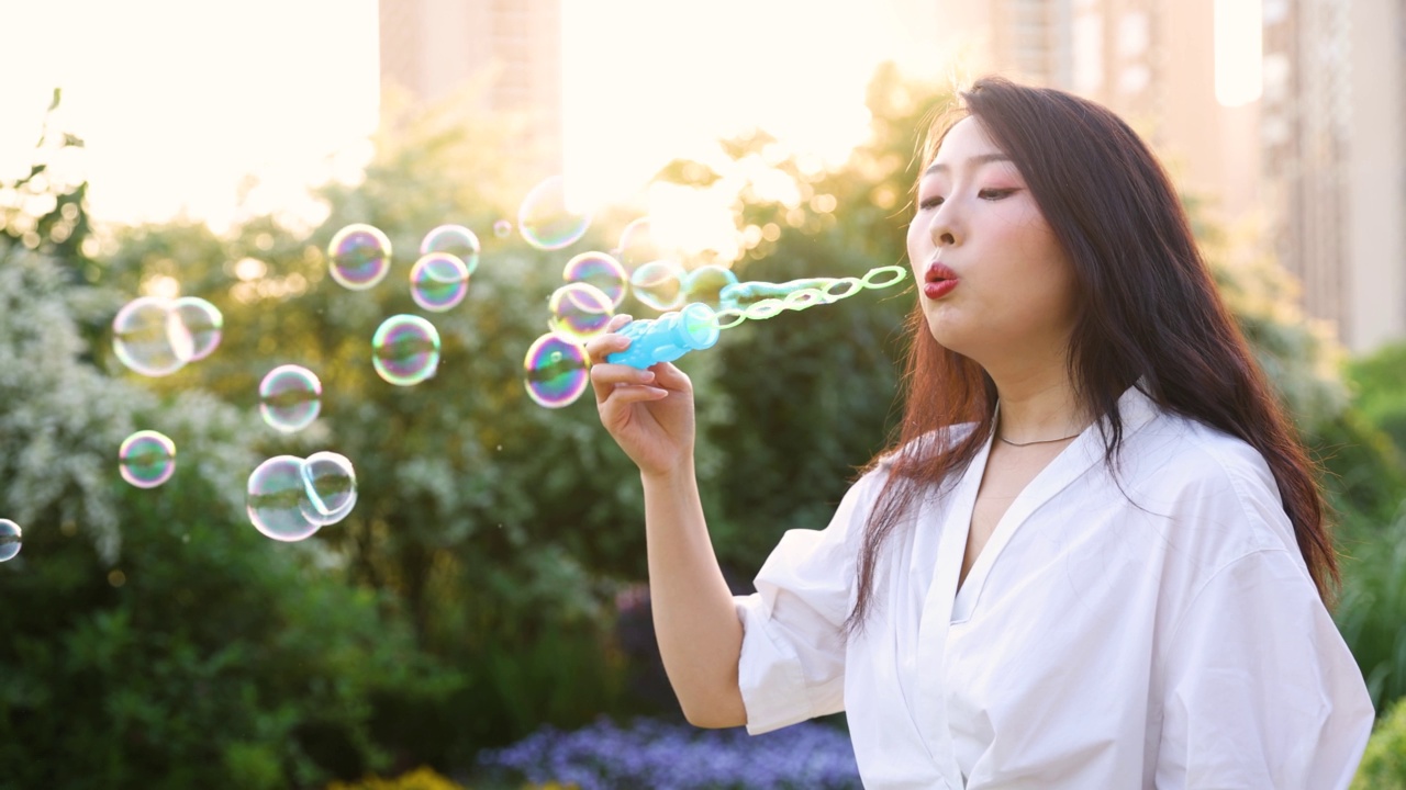 年轻女子在日落时吹肥皂泡视频素材