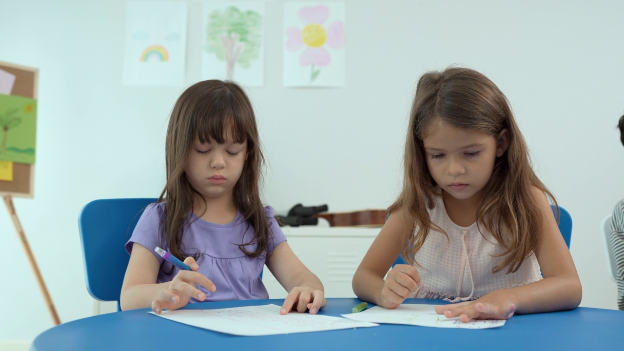 两个孩子一起在室内的桌子上用彩笔画画。幼儿园游戏活动。第一次到学校接受教育和在幼儿园玩耍，还是学龄前儿童在家学习的概念。视频素材