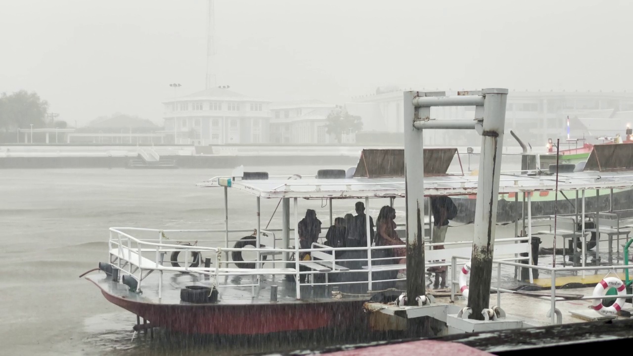 闪电风暴袭击曼谷，带来强风和暴雨，导致洪水泛滥。乘客在曼谷湄南河渡船码头被困在恶劣的条件下，阿伦在背景中。雾多雾雷暴闪电极端天气条件视频素材