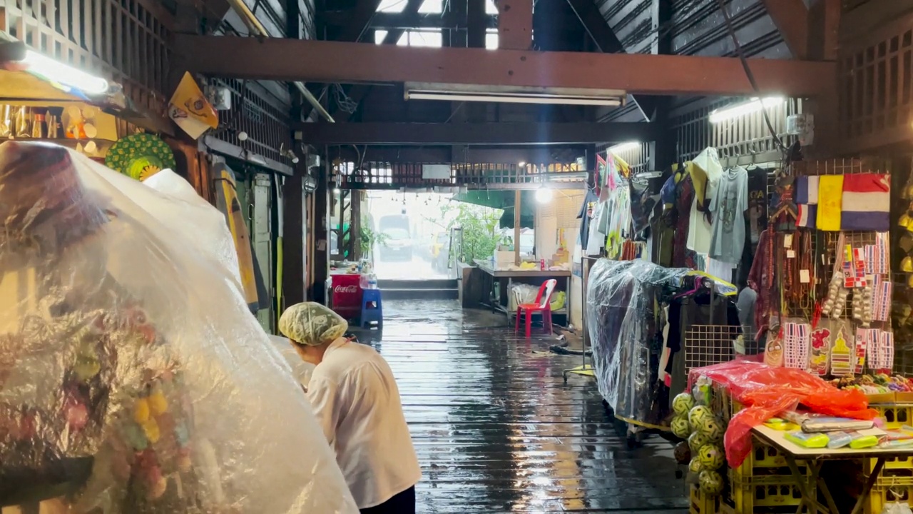 闪电风暴袭击曼谷，带来强风和暴雨，导致洪水泛滥。在曼谷湄南河渡船码头，乘客被困在恶劣的条件下，泰国女士试图保护他们的商店出售的旅游饰品和物品视频素材