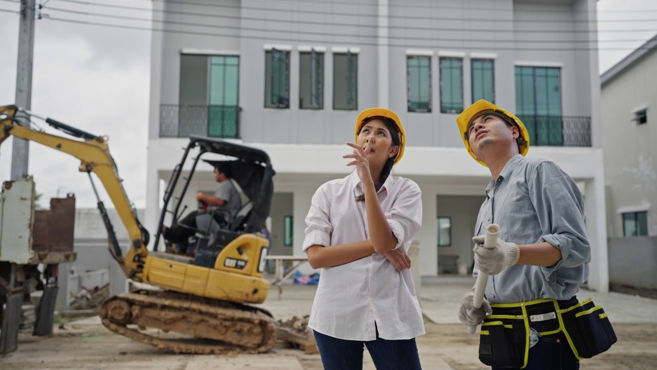 年轻的建筑师夫妇在住宅建筑工地讨论和观看蓝图。视频素材