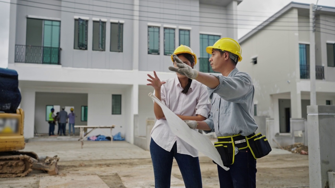 年轻的建筑师夫妇在住宅建筑工地讨论和观看蓝图。视频素材