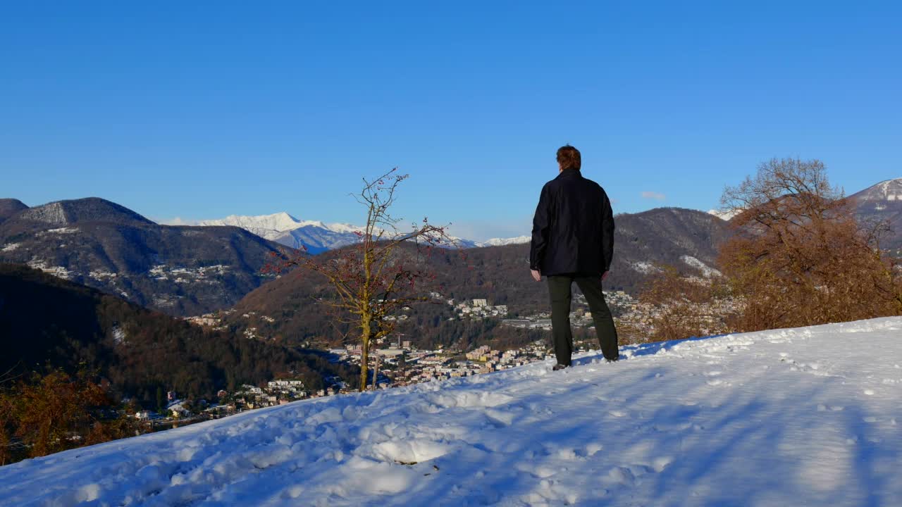 优雅的男人站在与手臂高举和喜悦山景与雪和晴朗的蓝天在晴朗的一天视频素材