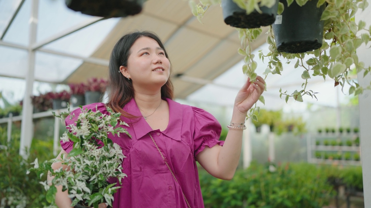 亚洲女性顾客在花园商店购买绿色植物，一位年轻女士在花卉市场选择观赏植物，家居和花园概念。视频素材