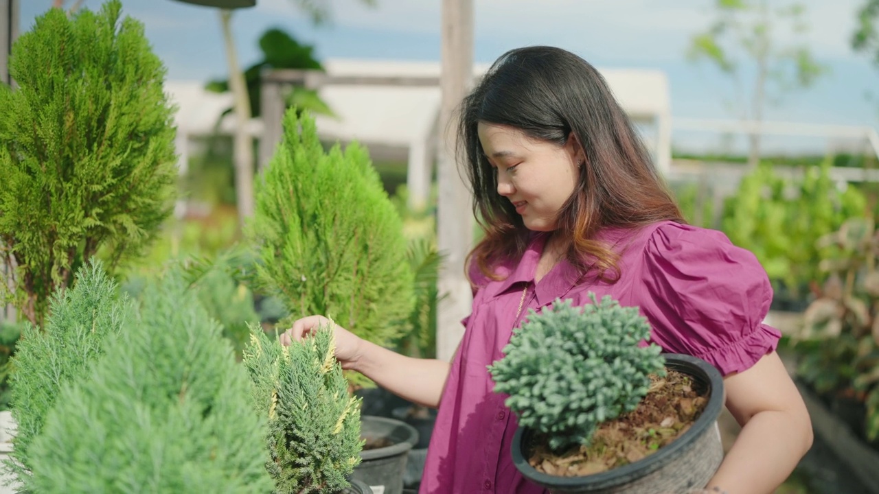 亚洲女性顾客在花园商店购买绿色植物，一位年轻女士在花卉市场选择观赏植物，家居和花园概念。视频素材