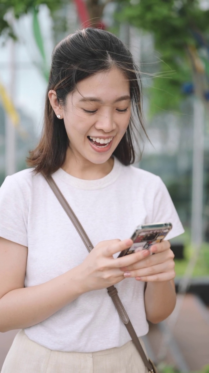 在泰国曼谷沙通，轻松的办公室女性使用数字设备进行户外移动银行支付视频素材