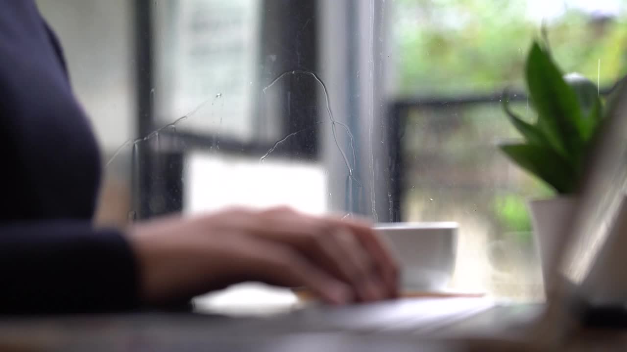 在电脑键盘上打字的女商人专业用户数据表打印概念在雨季，女商人一边喝咖啡一边工作视频素材