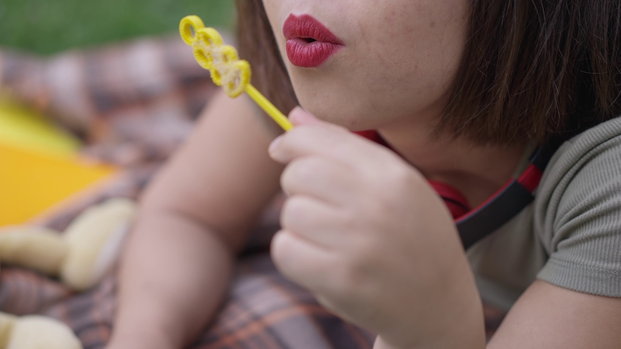 在户外吹肥皂泡的白人小女人的嘴唇。轻松、无忧无虑、快乐的侏儒少年周末在公园里享受夏日春夏的休闲。视频素材