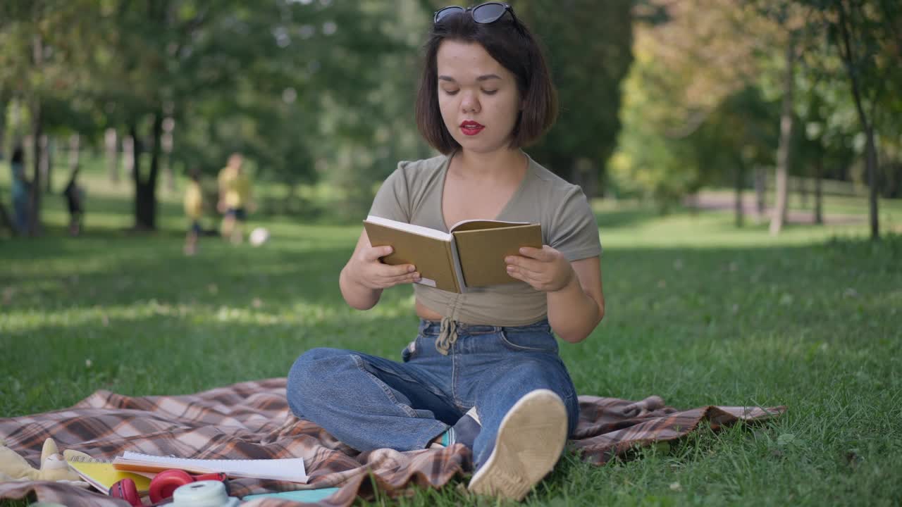 快乐的年轻女子与侏儒拥抱书读浪漫的诗在夏天的公园。宽镜头肖像高加索小人儿享受周末户外爱好。视频素材