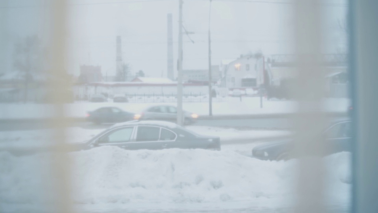 汽车行驶在雪城的道路上。从工厂大楼的窗帘上看出去。视频素材