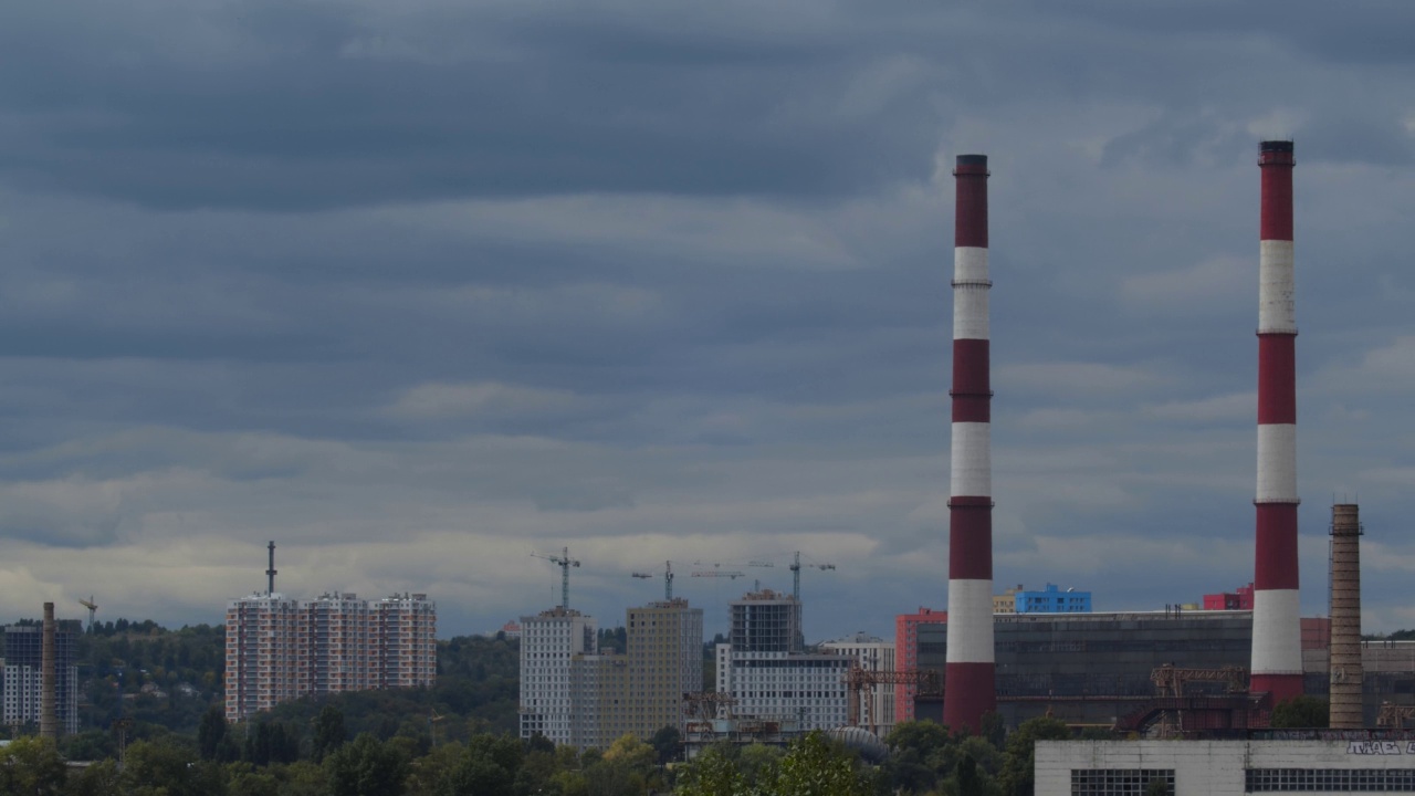 城市工业景观上空运行的云的超高速摄影。现代化的城市景观，建筑行业的吸烟管道和起重机视频素材