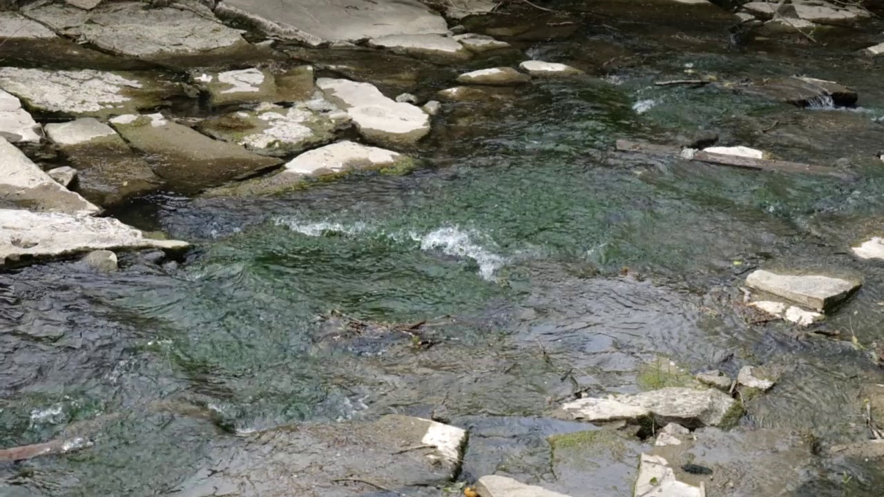 水和岩石一起流入河里。慢镜头河视频素材