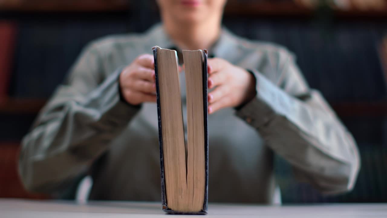 特写面目全非的女人打开图书馆书桌上的古旧纸质书教育科学信息视频素材