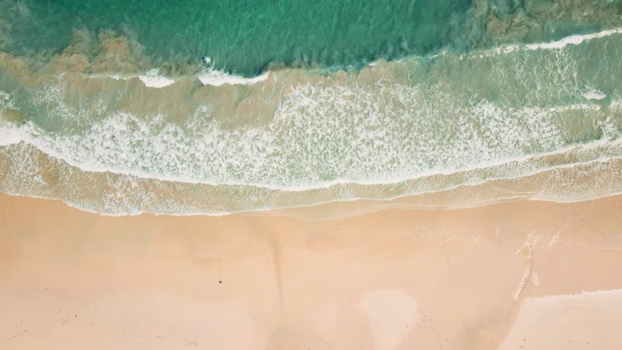 夏季局部沙滩和海浪。无人机鸟瞰图。沙滩上冲浪的俯视图。美丽的日落白色沙滩。完美的假期夏季背景。缓慢的运动。视频素材