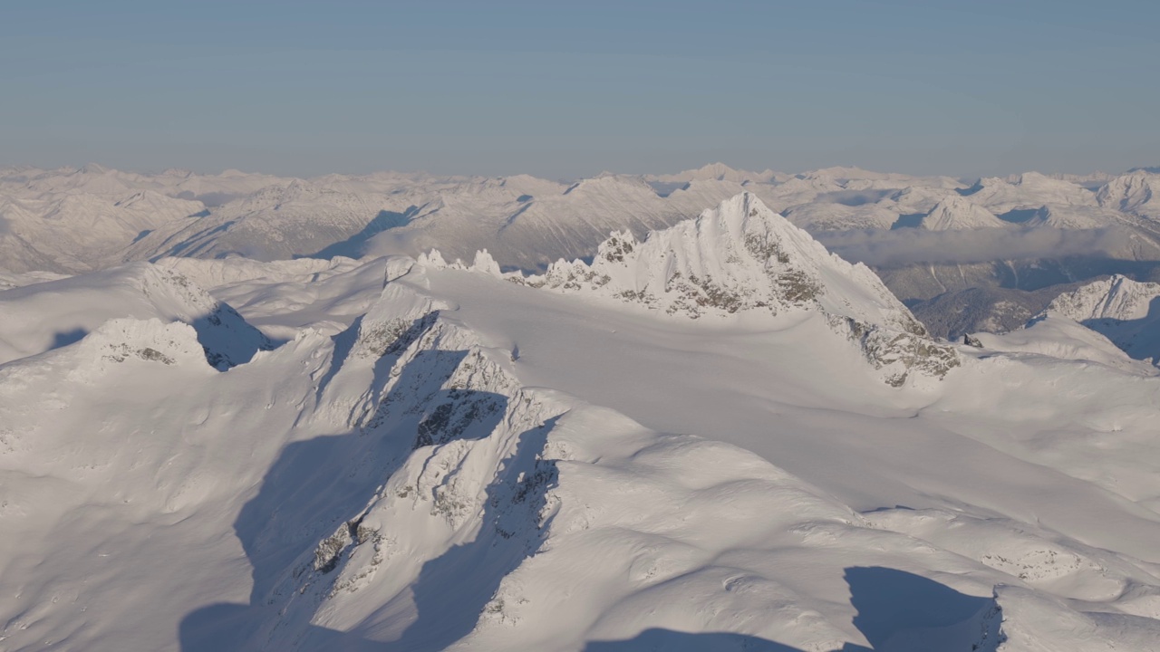 在阳光明媚的冬季，加拿大山被雪覆盖的空中全景视频素材