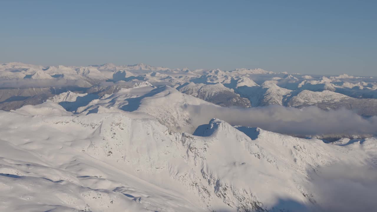 在阳光明媚的冬季，加拿大山被雪覆盖的空中全景视频素材