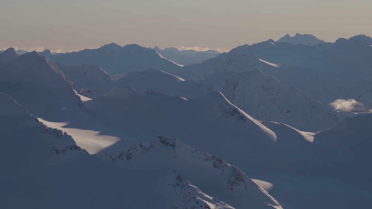 在阳光明媚的冬季，加拿大山被雪覆盖的空中全景视频素材