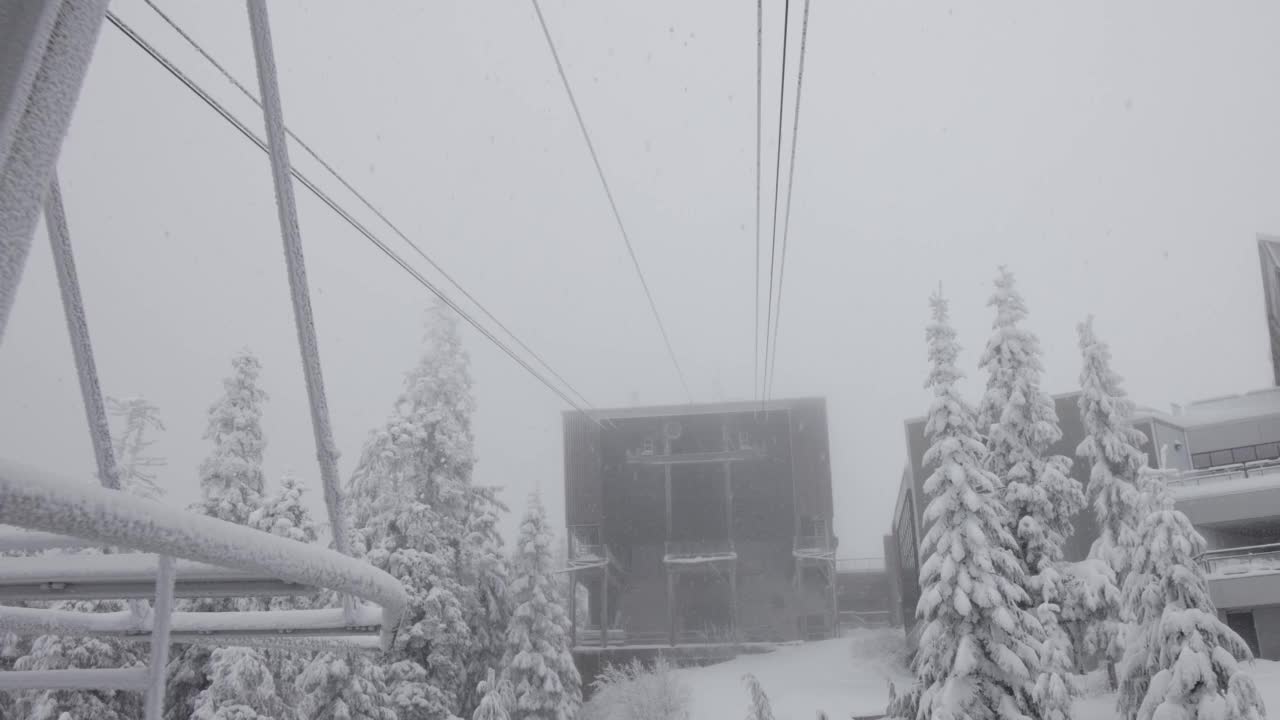 鸟瞰缆车塔，俯瞰白雪覆盖的常青树和岩石峭壁视频素材