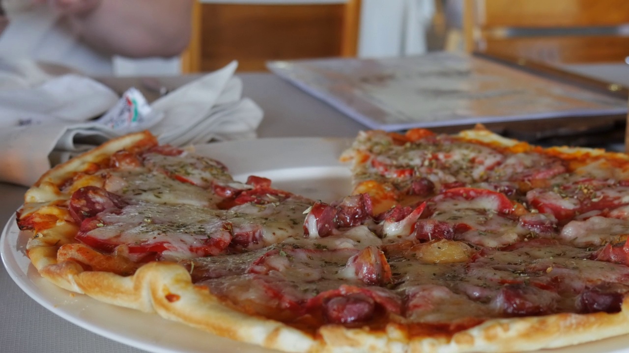 在餐厅的餐桌上用手拿着一片有弹性芝士的披萨视频下载