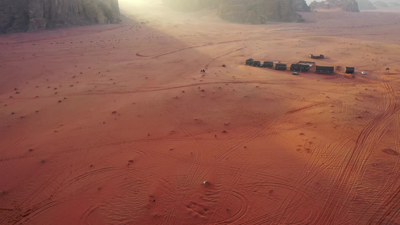 空中拍摄的人们在瓦迪拉姆沙漠骑骆驼，无人机向前飞行的景观视频素材