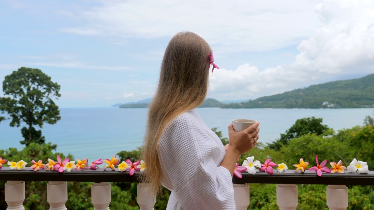 女人喝咖啡装饰露台热带花卉海景视频素材