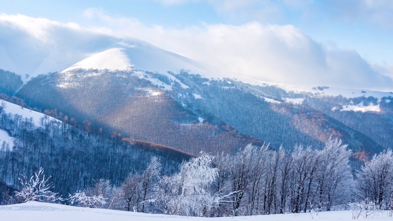 高山峻岭的风景鸟瞰。冬日阳光下的壮丽景色。蓝天，雾和雪的时间推移视频。4K背景潘拍摄的喀尔巴阡山在乌克兰视频素材