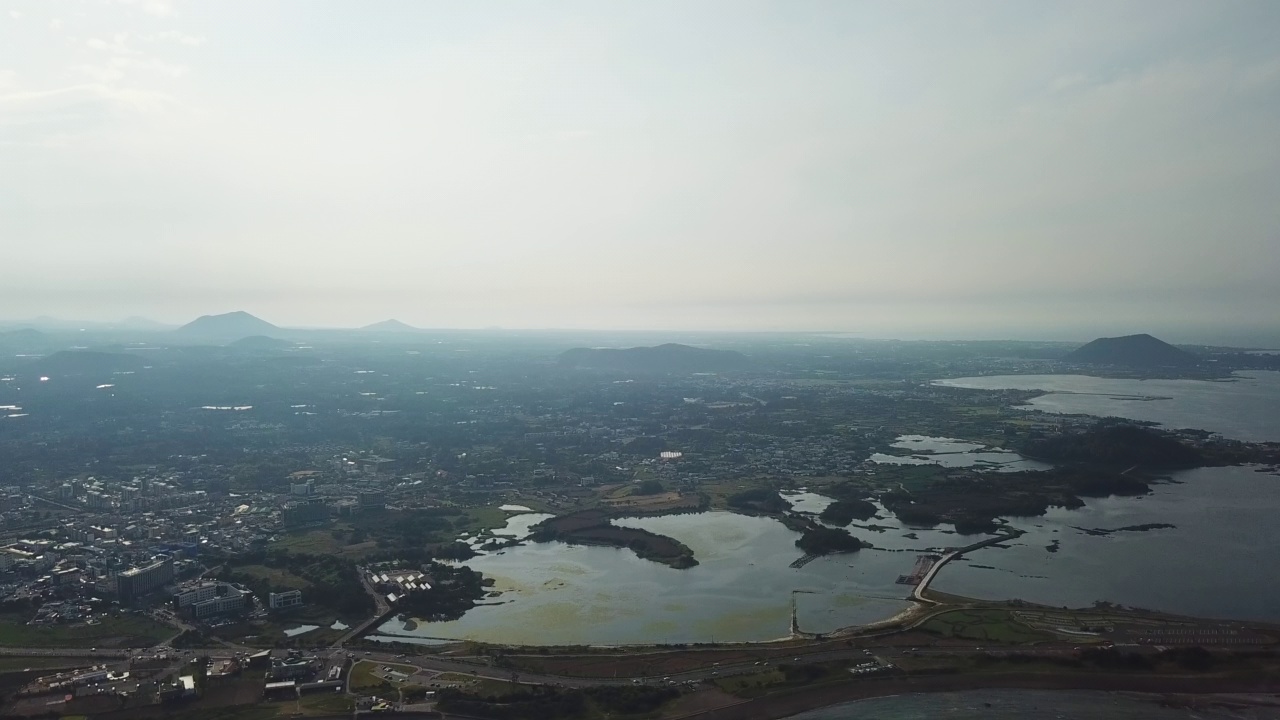 村庄、山、火山锥、海-韩国济州岛西归浦市和济州市的九佐郡五佐浦港的城山郡和广志木海滩视频素材