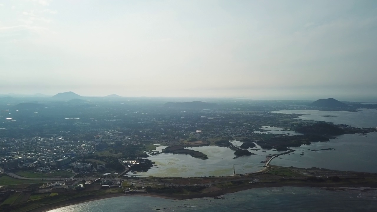 村庄、山、火山锥、海-韩国济州岛西归浦市和济州市的九佐郡五佐浦港的城山郡和广志木海滩视频素材