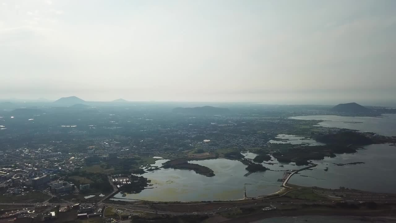 村庄、山、火山锥、海-韩国济州岛西归浦市和济州市的九佐郡五佐浦港的城山郡和广志木海滩视频素材