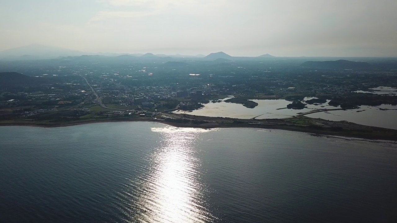 村庄，山，火山锥，海洋-圣山郡和广志木海滩在九州郡/西归浦市和济州市，济州岛，韩国视频素材