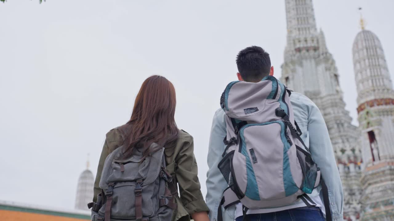 亚洲迷人浪漫情侣在城市旅行蜜月之旅。年轻的新婚男女背包客看佛寺，享受花时间在一起度假。视频素材