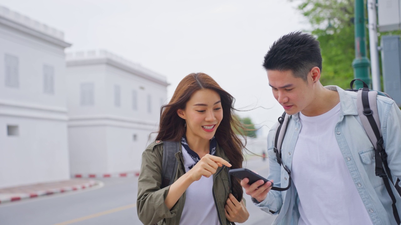 亚洲迷人浪漫情侣在城市旅行蜜月之旅。新婚男女背包客旅游用手机找目的地，一起享受度假时光。视频素材