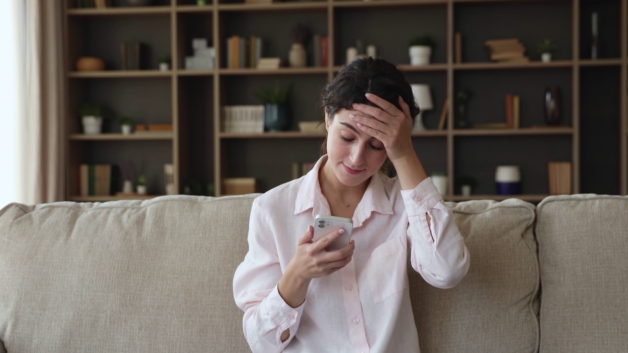 女人拿着手机看短信，带着坏消息看起来很沮丧视频素材