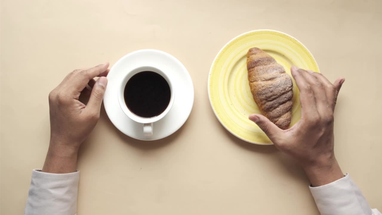 盘子里有新鲜出炉的牛角面包，桌上有一杯茶视频素材