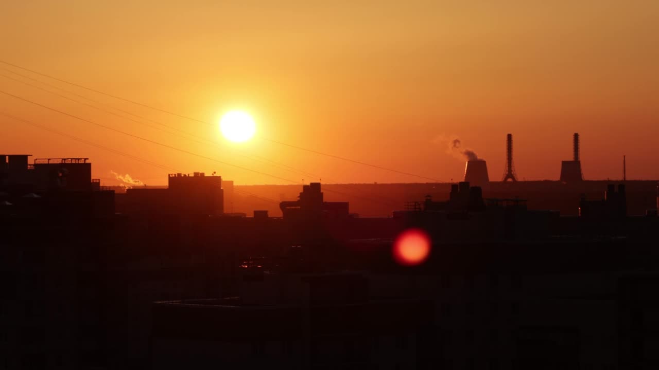 城市上空金色的夕阳。夕阳映照下的建筑物屋顶和企业管道视频素材