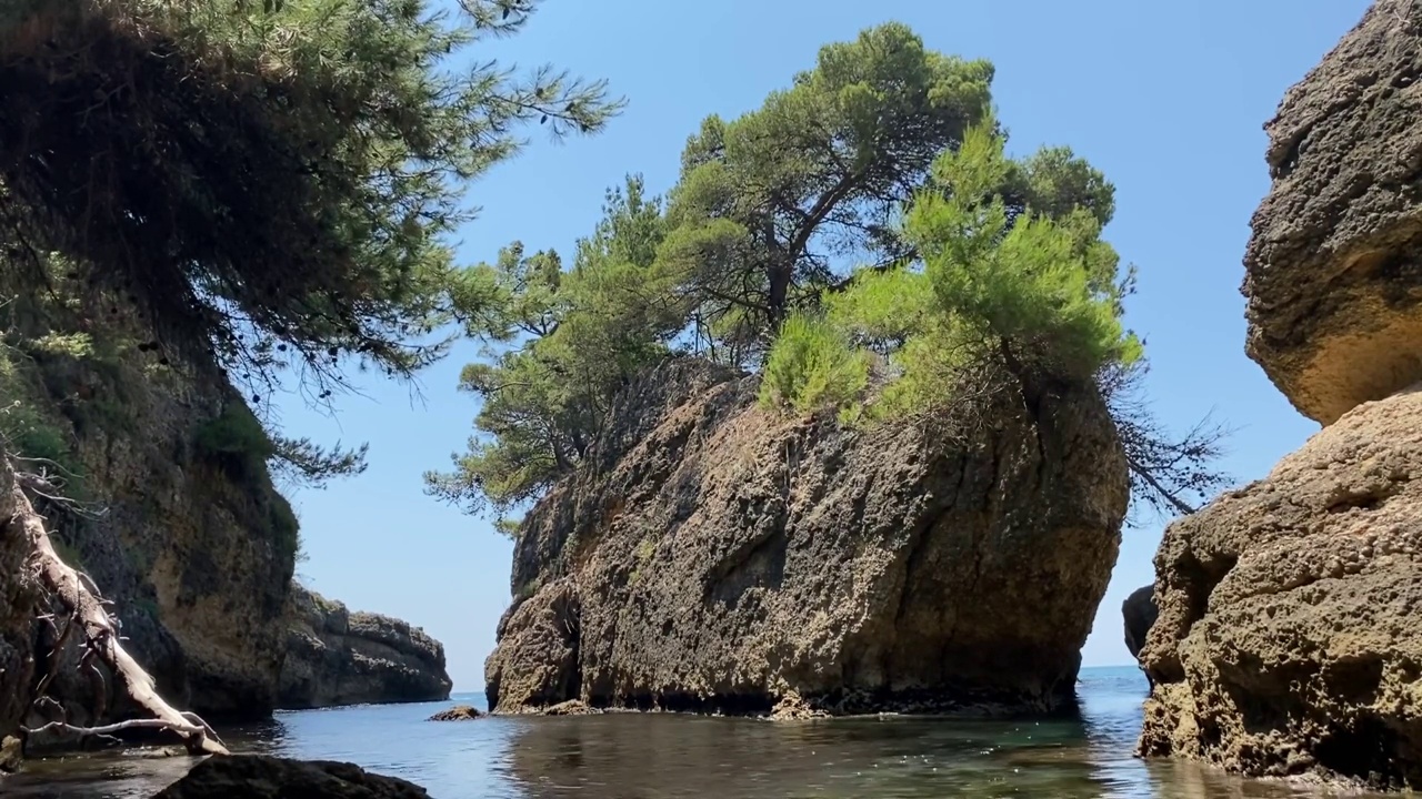 阳光明媚的夏天，地中海美丽的岩石海岸。风景优美的海岸岩石与松树。清晰的闪闪发光的水。视频素材