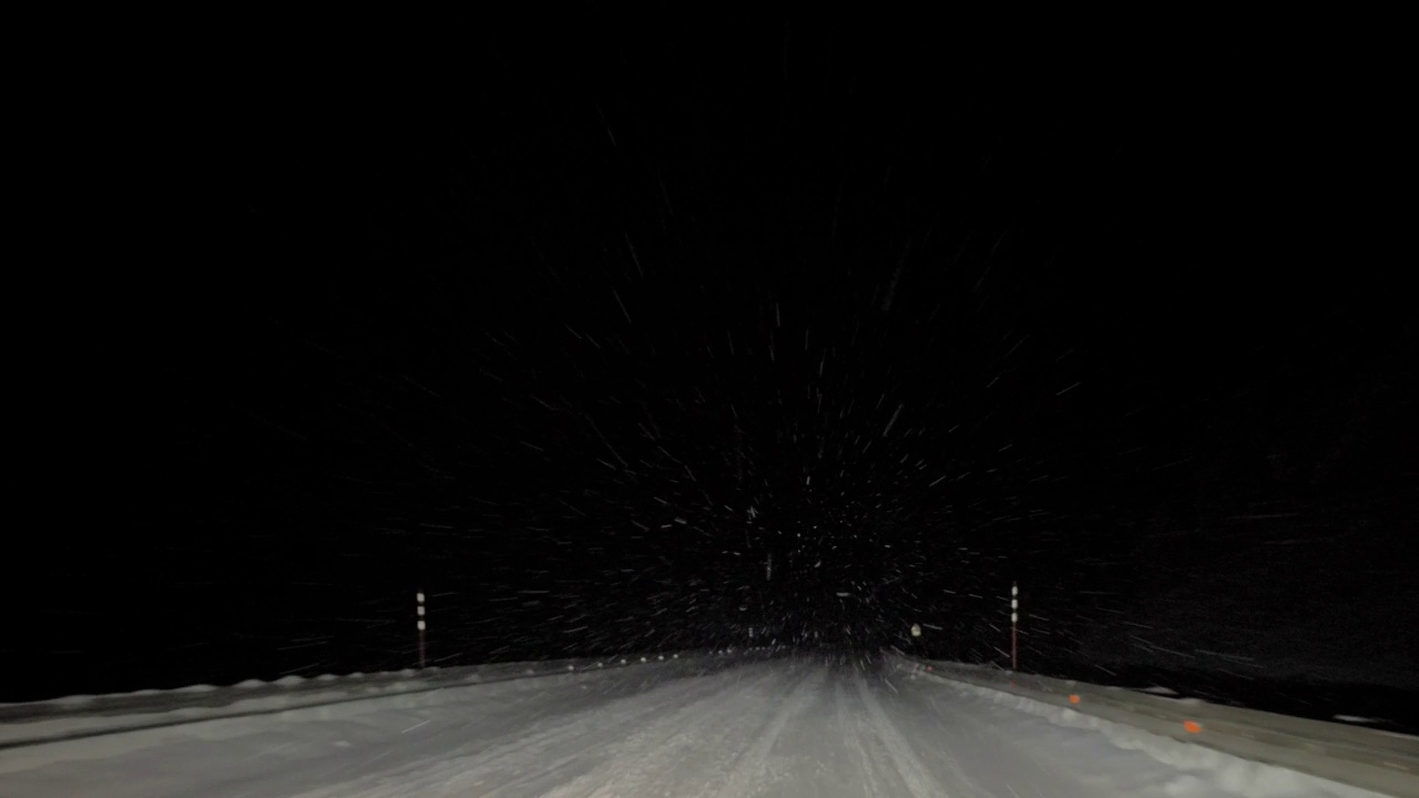 一辆汽车在大雪纷飞的夜晚行驶在路上。透过汽车挡风玻璃看。严重的暴风雪视频素材