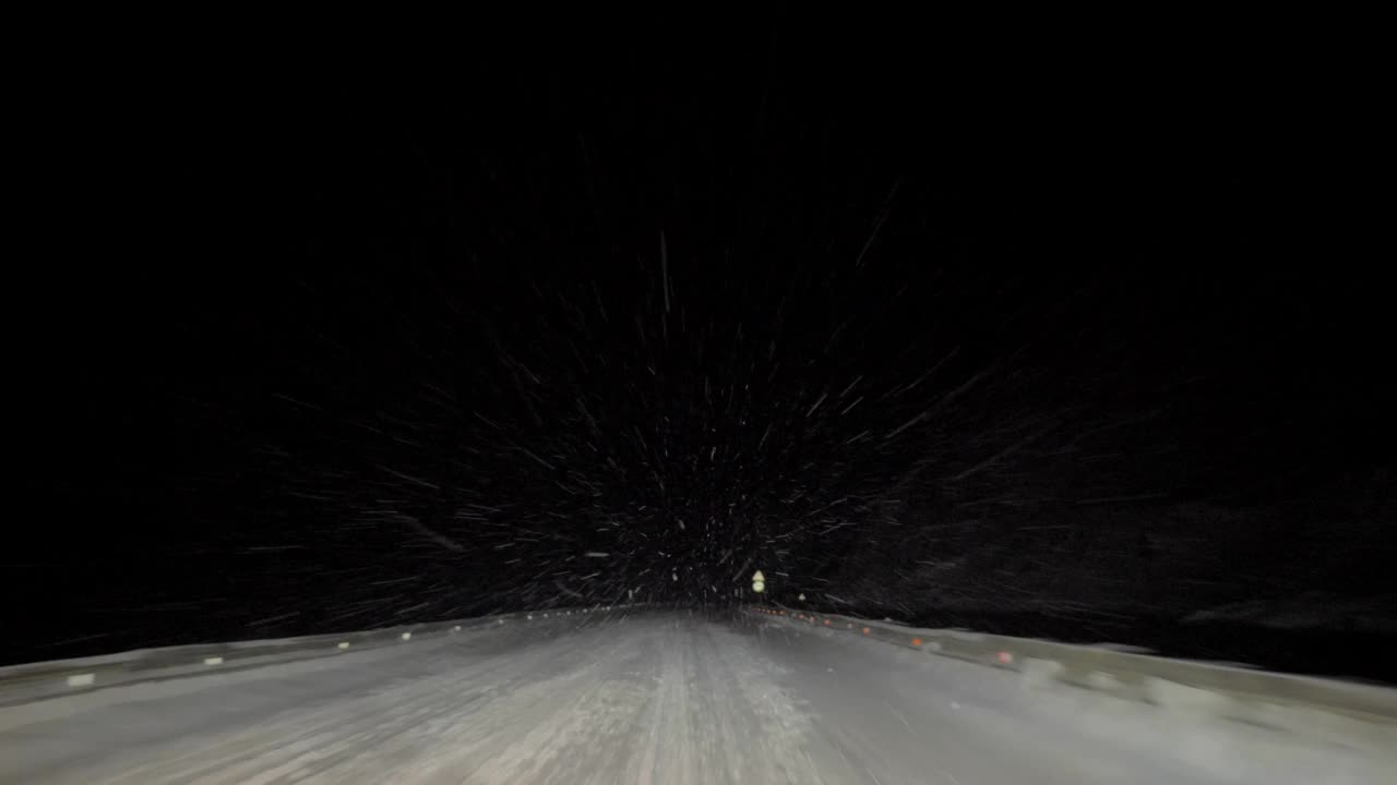 一辆汽车在大雪纷飞的夜晚行驶在路上。透过汽车挡风玻璃看。严重的暴风雪视频素材