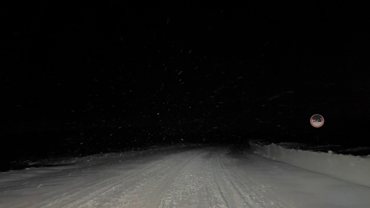 一辆汽车在大雪纷飞的夜晚行驶在路上。透过汽车挡风玻璃看。严重的暴风雪视频素材