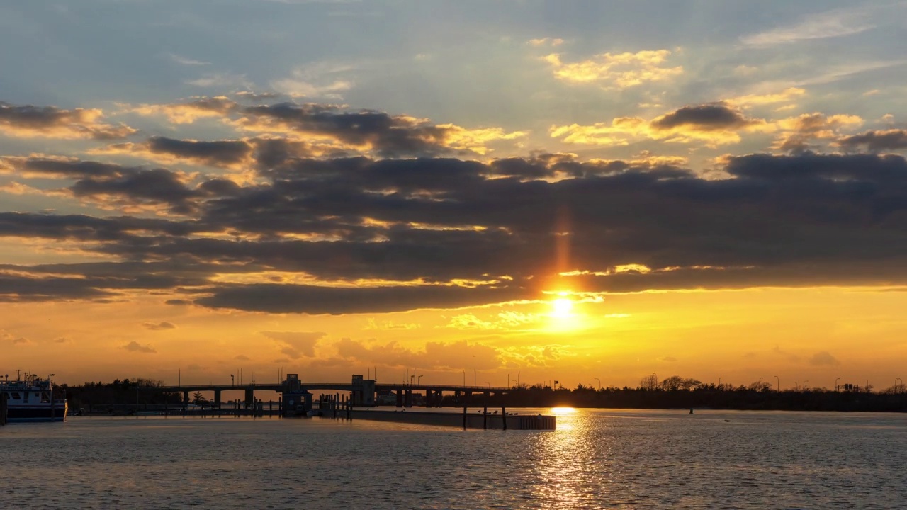 生机勃勃的沿海夕阳缓缓落下，有一座小桥横跨水面视频素材