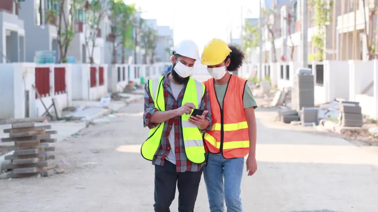 职业女性和男性工作者。非裔美国混血。建筑工人戴口罩在工作场所工作和行走视频素材