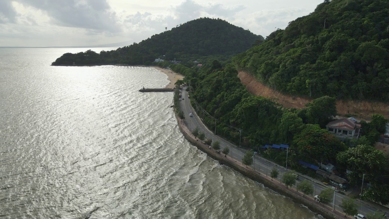 航拍向后拍摄的阳光与海边道路上海浪的阴影视频素材