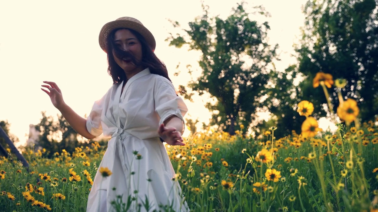 美丽的年轻女子在夕阳下的黄花草地上奔跑视频素材