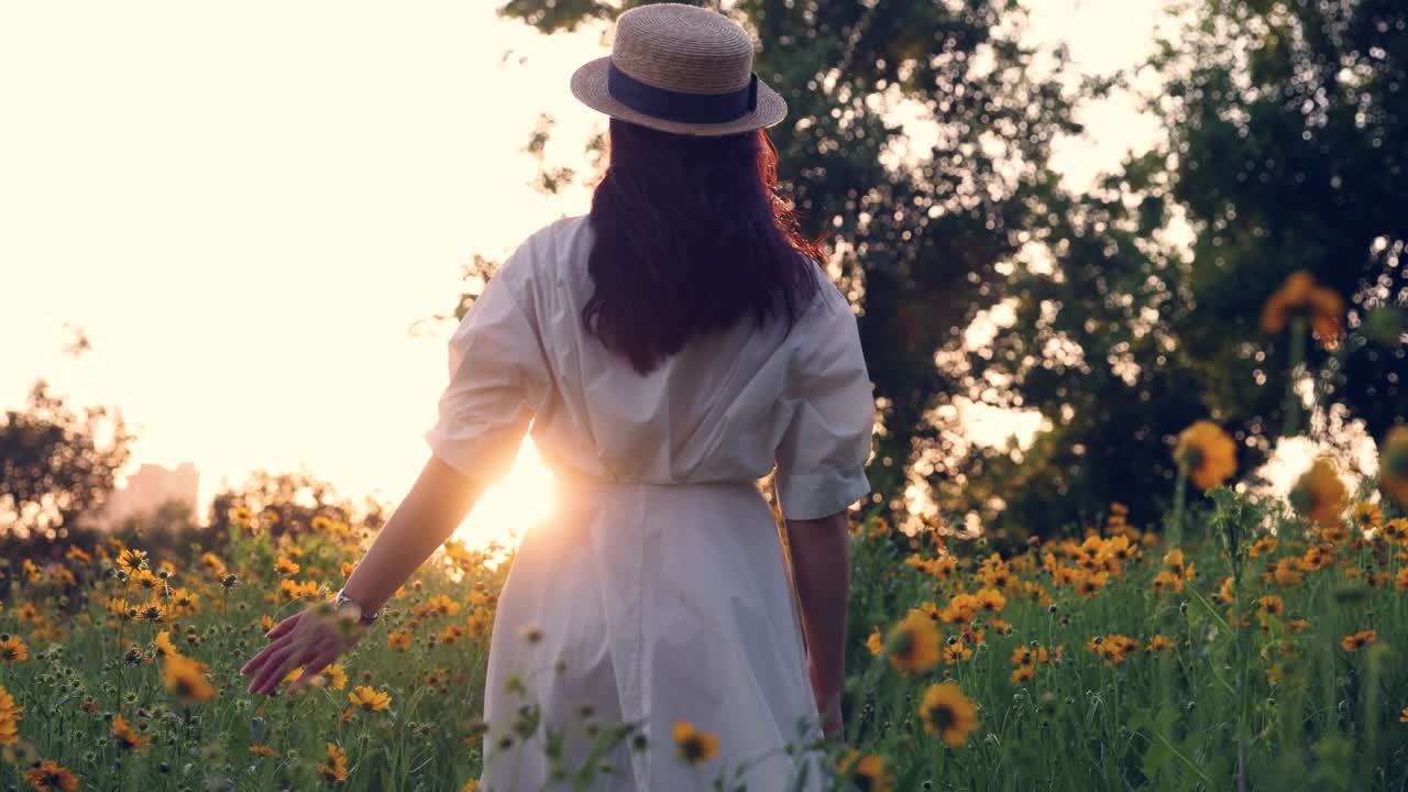 一个年轻女子穿过一片花田视频素材