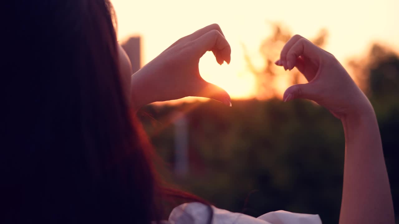 女人的手在夕阳下做出心形视频素材