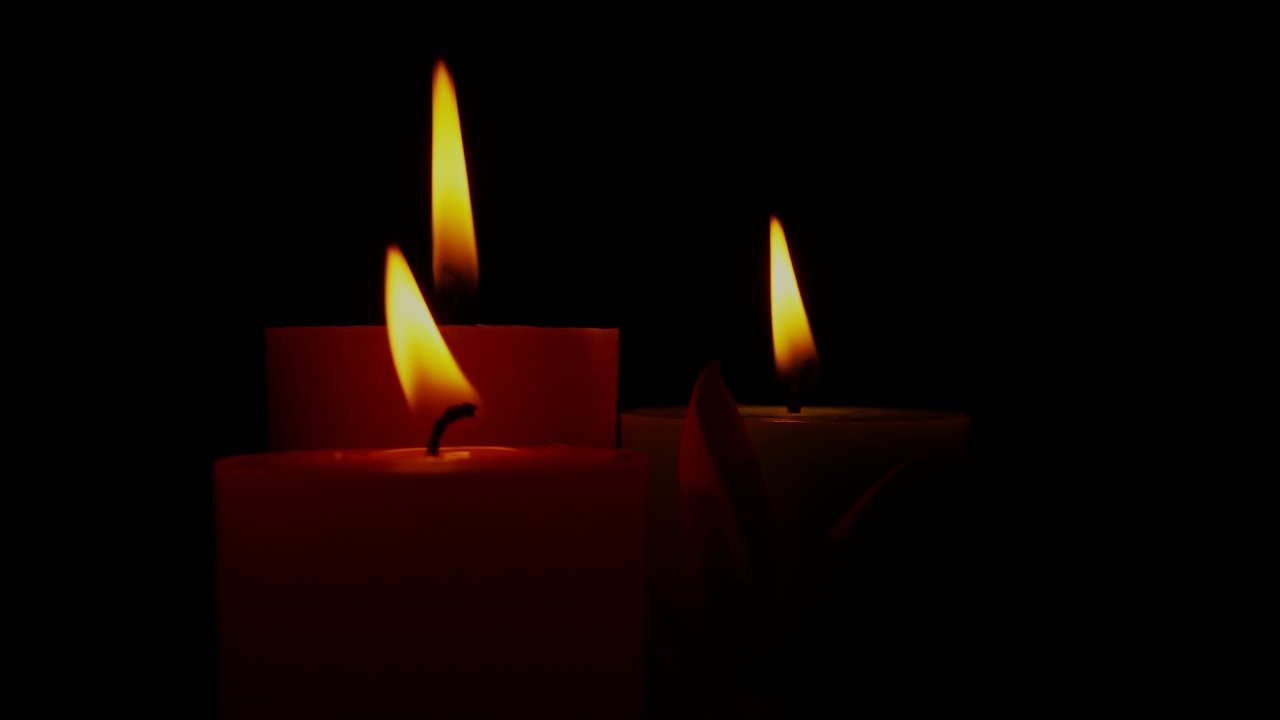 蜡烛火焰在风中轻轻摇曳。在黑暗中燃烧的蜡烛旋转。视频素材